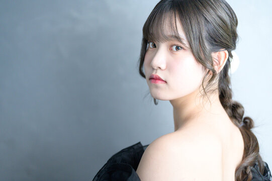 グレー背景で振り返る黒いドレスを着た日本人女性