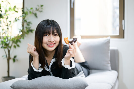 ベッドでドーナツを食べながらくつろぐ日本人女性