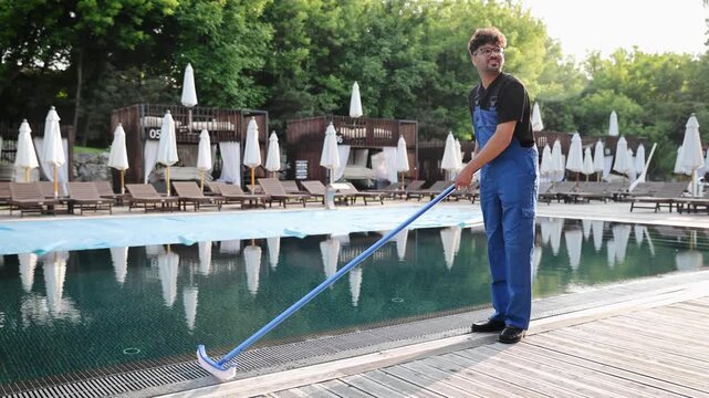 Hotel employee cleaning an outdoor swimming pool with a net, ensuring hygiene and offering quality resort services
