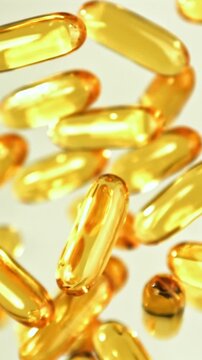 Golden softgel capsules shimmering in warm light, omega supplement Filmed on a high-speed camera at 1000 fps.