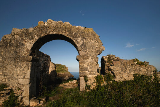 Detail of semicircular arch with sea views in the ruins of a medieval sanctuary by the coastline of Llanes, Asturias, Northern Spain