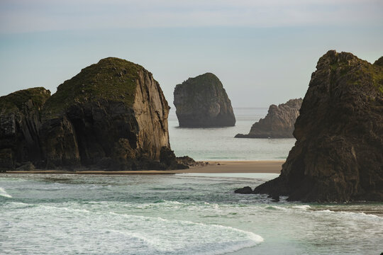 Small island with a sand tombolo in the rocky and wild coastline of Llanes, Costa Verde, Eastern Coast of Asturias, Spain