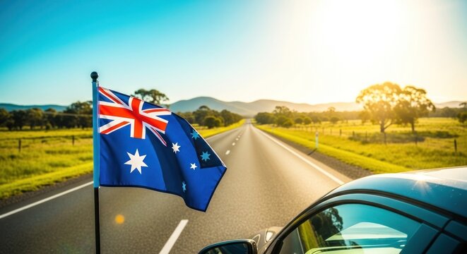 Australian flag waves on a car driving down a scenic road at sunset with mountains