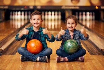 Fototapeta premium Happy Kids Celebrating Victory at the Bowling Alley with Thumbs Up