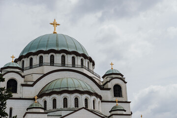 Fototapeta premium Large domes of Saint Sava Temple rise under dramatic clouds in Belgrade Serbia. Concept of religion, heritage, spirituality and architecture