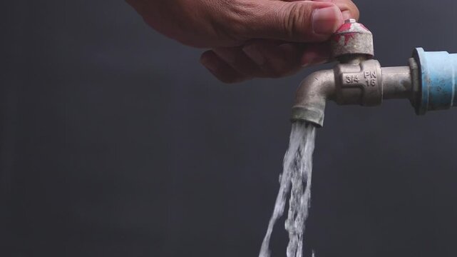 A hand turning a faucet to start the flow of clean water, symbolizing conservation and resource management