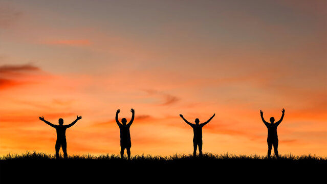 Four silhouettes of people with arms raised in the air against a vibrant sunset sky. They stand on a grassy hill, embodying freedom and triumph