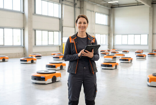 Female engineer managing autonomous mobile robots in a warehouse
