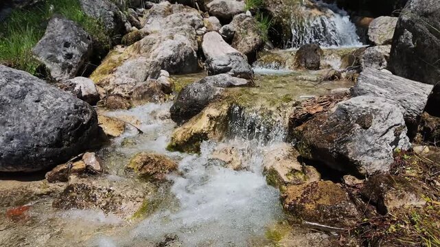 Clear mountain stream flowing over textured grey rocks, refreshing water splash, serene nature scenery, natural hydration and environment