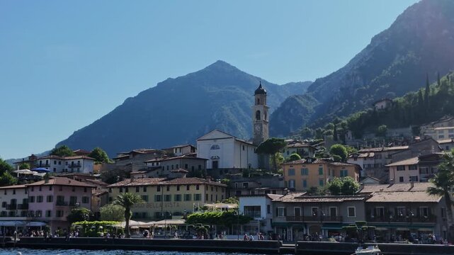 Scenic view of Limone sul Garda village on Lake Garda, featuring traditional Italian architecture, waterfront promenade, and dramatic mountain backdrop
