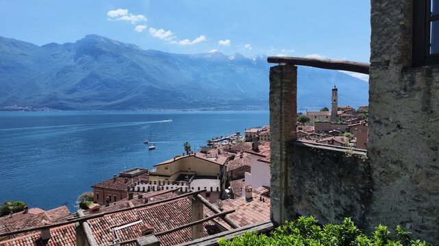 Panoramic view over Limone sul Garda with terracotta roofs blue water and mountains, travel destination, italian landscape summer vibes