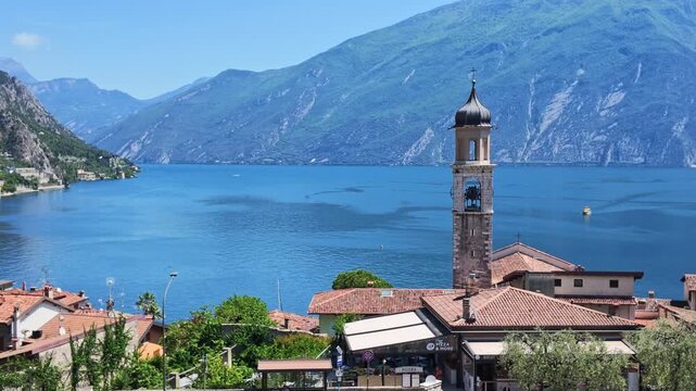 Scenic view over Limone sul Garda with Italian village architecture, ancient bell tower, mountains and deep blue lake waters