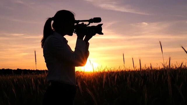 Sequence of a female filmmaker shooting with a professional camera during golden hour. Silhouette of a videographer working outdoors in a rural field against the sunset