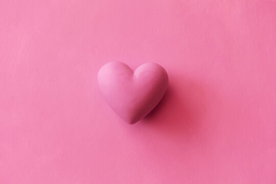 pink volumetric heart on plain background. Monochrome background with copy space for Valentine's Day and holiday of love.
