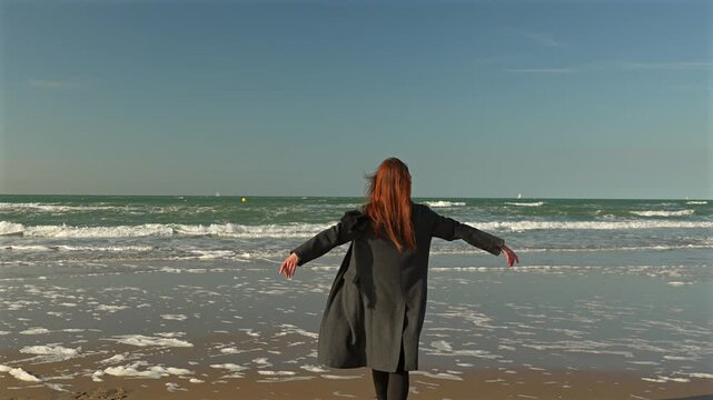 Woman standing on sandy beach in Dunkirk France during spring