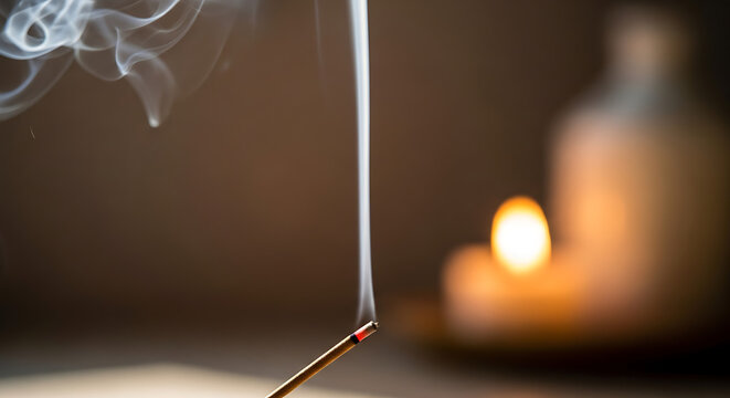 Burning incense stick with smoke on a blurred background with candle light
