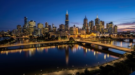 Obraz premium City skyline illuminated at dusk with river reflections and lit bridges spanning calm water along waterfront promenade and urban lights