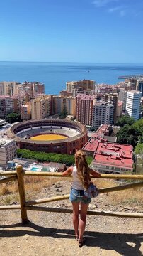 high angle view of a female tourist looking at plaza de toros and malaga city skyline. Tour tourism in Spain