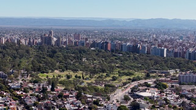 Aerial view of Cordoba city skyline with large urban park and traffic avenue, Argentina.
