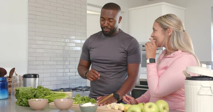 African American couple at home tasting as man lifting bite checking taste cutting salad with knife