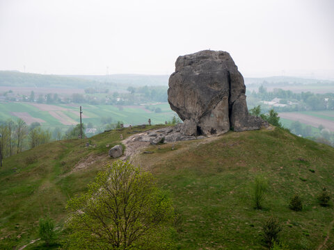 Devils Stone boulder standing on spring hill in Pidkamin rural landscape