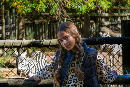 Young girl smiles beside zebra enclosure