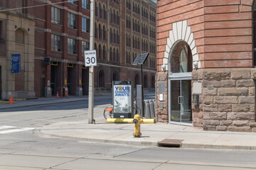 Naklejka premium looking north at crossing of Frederick St and King St E to Bike Share Toronto rental bike docking station and wayfinder at George Brown College, Toronto