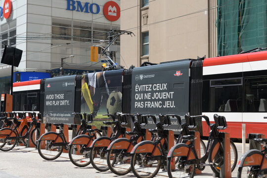 Bike Share Toronto docking station, trolley with ad wrap for Competition Bureau Canada, crossing King St W and Bay St near First Canadian Place, BMO Bank of Montreal