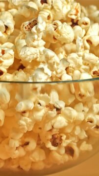 A bowl of popcorn falls on a yellow background. Filmed on a high-speed camera at 1000 fps. High quality FullHD footage