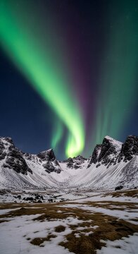 Photo of vibrant aurora borealis dances across a starry night sky above snowcapped mountains