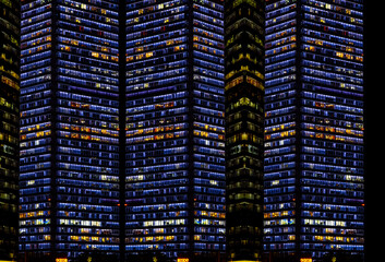Multi-stories office building at night with worker working overtime. late night at office. lighting and working people within © Roberto Sorin