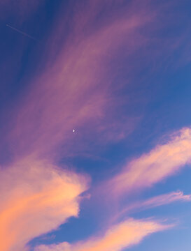 Pastellfarbener Abendhimmel mit zarten Wolken und dem Halbmond