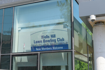 Naklejka premium Wells Hill Lawn Bowling Club sign inside window of Toronto Public Library - Wychwood Branch - 46 Melgund Rd 