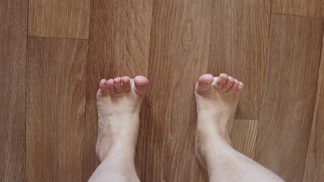 Feet of Caucasian woman on floor barefoot, lifting toes upward. POV of orthopedic foot exercise to correct problem. Foot gymnastics and leg warm-up.