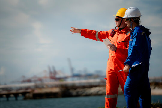 two professional engineer, worker, technician use clipboard discuss work, factory plant industry at a gas storage facility. protective uniforms and helmets. industry, engineer, safety, teamwork.