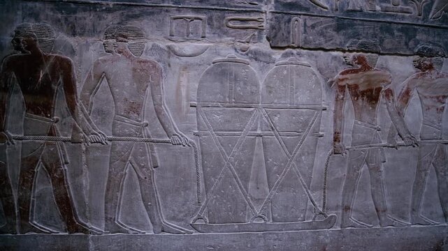 Close-up of detailed limestone relief carving inside tomb of Kagemni at Saqqara, Egypt, depicting ancient Egyptian male figures with tools, faint traces of original red pigment.