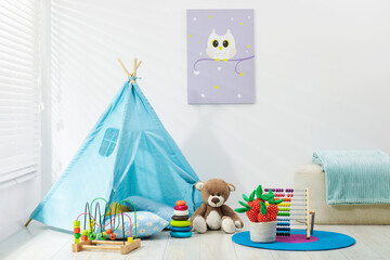 Wigwam, toys, pouf and pillows near white wall in child's room © New Africa