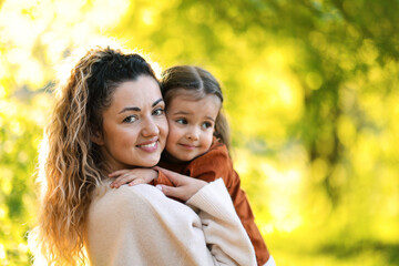 Fototapeta premium Mother with her cute little daughter in nature on sunny day. Space for text