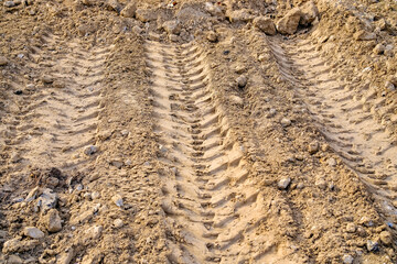 Heavy machinery tire tracks on dry clay soil at construction site with rough textured ground and excavated earth © Dmitrii Masquerade