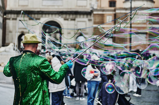 street performer creating massive soap bubbles for tourists and locals in Piazza del Popolo, a grand, historic neoclassical square, Rome, Italy, Europe 