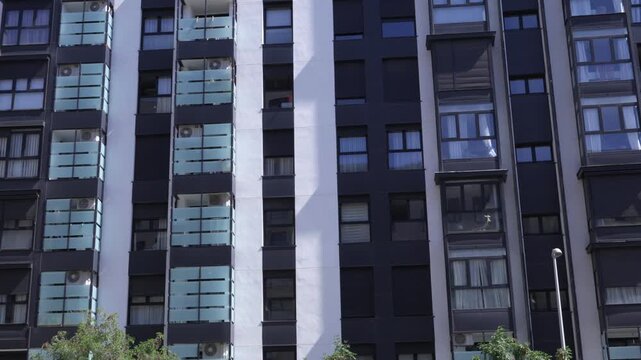 Close architectural view of a contemporary residential apartment facade featuring repetitive balconies, windows and geometric urban design patterns