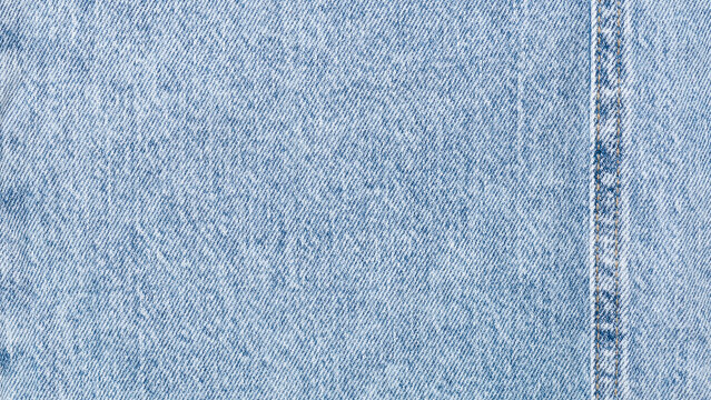 Close up of light blue denim fabric texture with visible weave and soft washed effect background