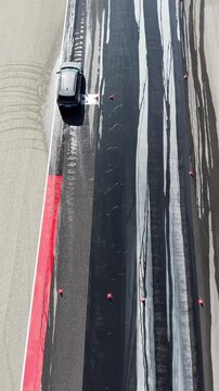 Vertical Aerial Top Down View of Car Driving on Race Circuit Tarmac