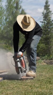 Landscaping worker using a concrete saw to cut paving stones with heavy dust cloud 4k