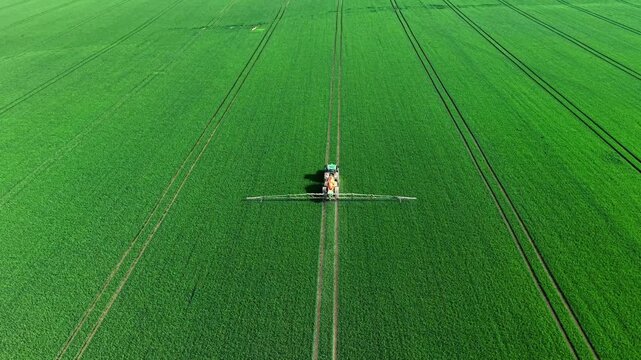 Aerial View of Tractor Spraying Vast Green Field with Converging Tramlines