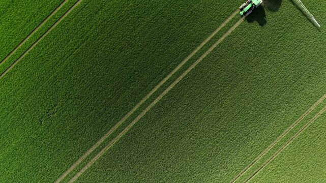 Aerial Top Down View of Tractor with Sprayer Working Green Field