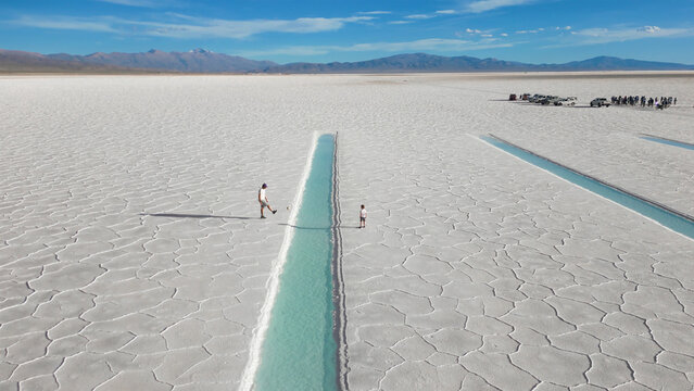 Aerial view of father and child playing soccer onwhite salt flats Salinas Jujuy Argentina