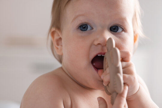 First baby teeth. Cute child with teether at home