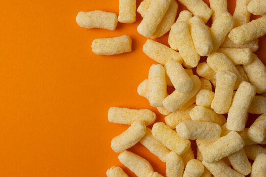 Crunchy Corn Puffs Closeup. Playfully Scattered Puffed Corn Pieces On Vibrant Surface For Advertisement