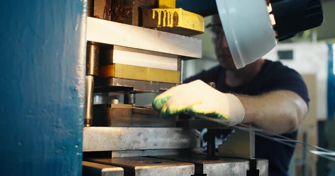 Hands of factory worker adjusting metal part in press mold. Precision manufacturing and industrial workflow close-up